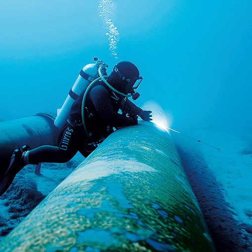 A solitary diver inspecting an underwater pipeline in the deep b