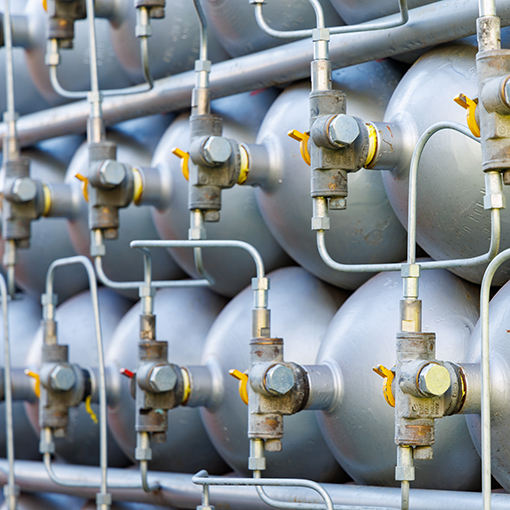 A lot of bottles filled with gas or gasoline are stacked in pile